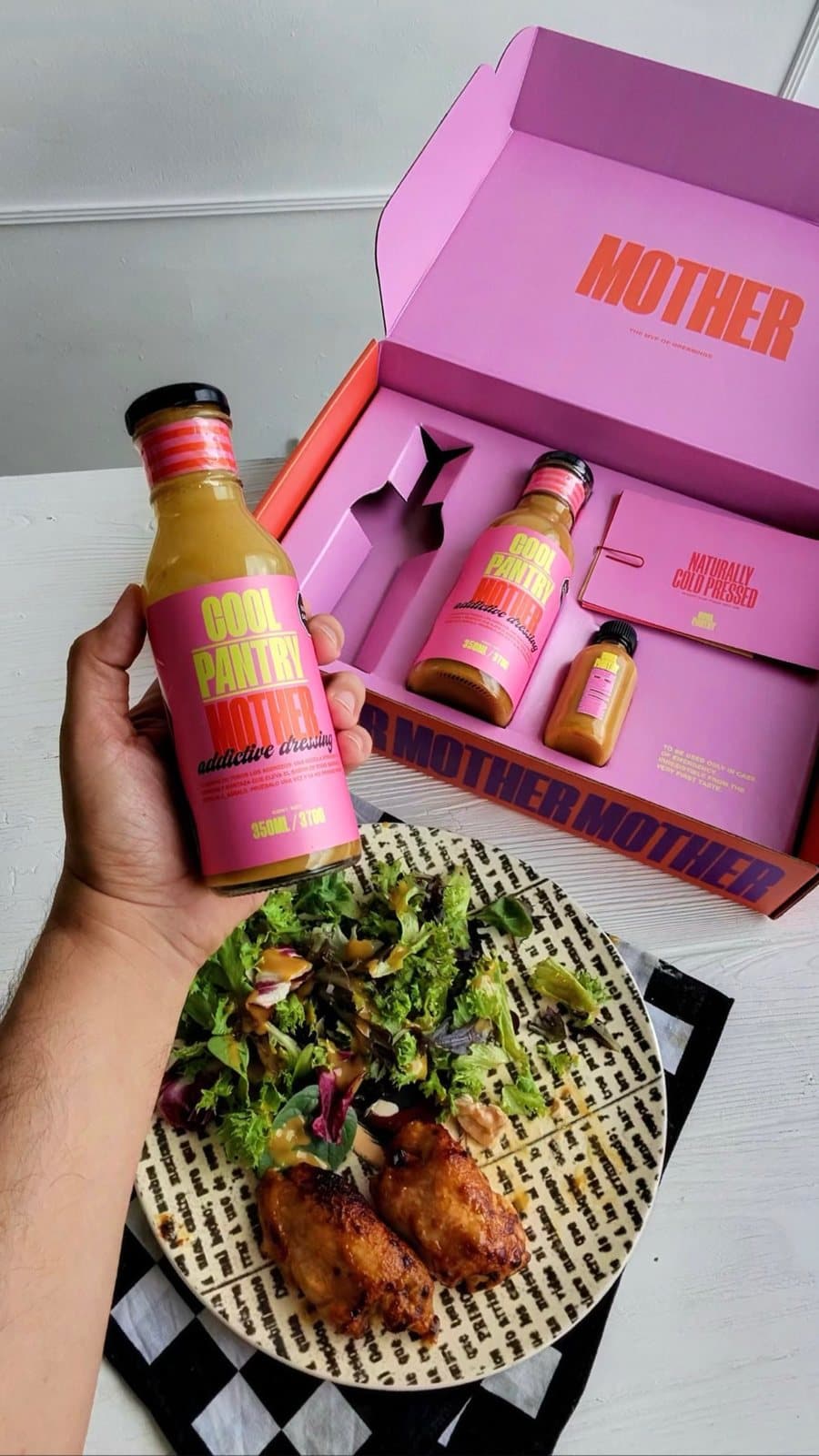 Mother junto a un plato de pollo y ensalada, con su caja rosa al fondo